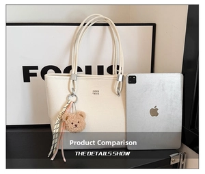 Grand sac cabas beige avec motif pierre et pendentif ours présenté à côté d'une tablette