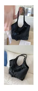 Close-up of black ruffled tote bag showing layered texture and long shoulder straps