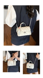 Detail of quilted beige shoulder bag with metal lock and silk scarf wrapped on handle