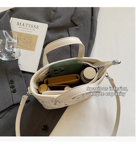 Internal capacity of white quilted bucket bag showing storage for phone and cosmetics