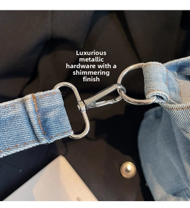 Detail of light blue denim bag featuring silver metal hook and orange contrast stitching
