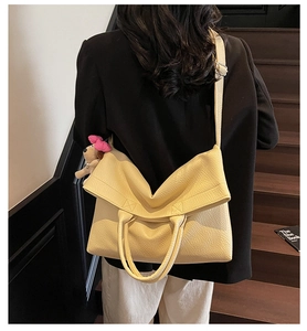 Detalle de bolso tote beige en cuero granulado con colgante de cachorro en la bandolera