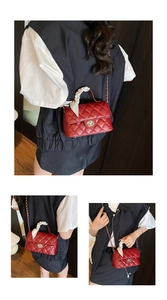 Detail of red quilted handbag with gold circular twist lock and silk scarf handle wrap