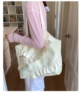Detail of cream nylon tote bag featuring ruffled layers and a silver D-ring ornament