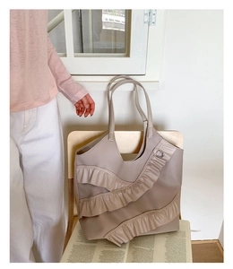Detailed close-up of khaki pleated ruffle nylon tote bag on a wooden chair with magazine