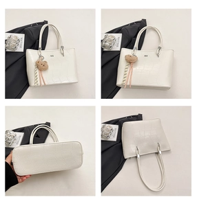 Détail du sac cabas blanc à motif crocodile avec breloque ours et finitions argentées