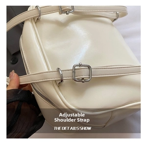 Detail of adjustable shoulder strap with silver metal buckle on cream tote bag
