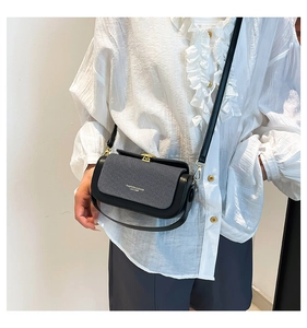 Detail of elegant black and grey crossbody box bag with gold buckle and leather texture