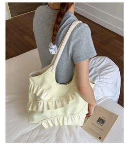 Detail of soft cream tote bag with elegant ruffle layers in a cozy lifestyle setting