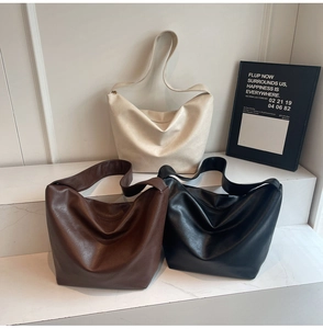 Three large hobo bags in off-white, brown, and black displayed on modern minimalist steps