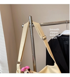 Primer plano del bolso tote de cuero granulado beige con hebilla y charm de perro de peluche