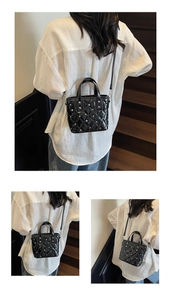 Close-up of black quilted bucket bag with silver studs on indoor wooden stairs
