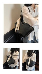 Detail of black tote bag with V-cut design, glossy texture and decorative ribbon