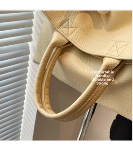 Detalle de cuero con textura de lichi amarillo y costuras reforzadas en un bolso tote