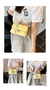 Detail of yellow quilted crossbody bag with decorative scarf handle and metal clasp