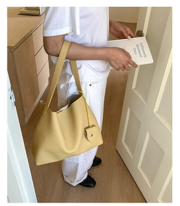 Borsa tote gialla in pelle martellata indossata da una modella in un moderno ambiente interno