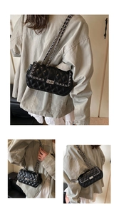 Detail view of black quilted leather shoulder bag with gold chain and metal lock