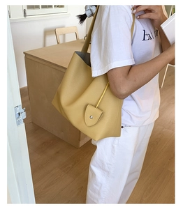 Dettaglio della borsa tote gialla in pelle martellata con patta e rivetto argentato