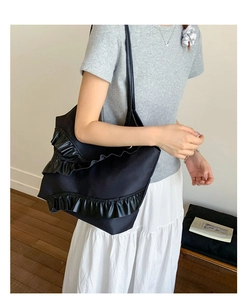 Detail of black nylon tote bag featuring three layers of shiny leather ruffles on the front