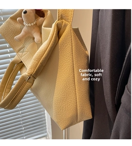 Detalle de bolso tote de cuero granulado blanco hueso con un colgante de perro de peluche
