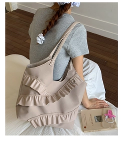 Detail of beige tote bag with lace-edge ruffles and spacious interior for daily use