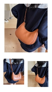 Detail view of a brown crescent shoulder bag with smooth leather finish and fine stitching
