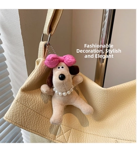 Detalle de llavero de peluche con lazo rosa en un bolso de cuero granulado beige