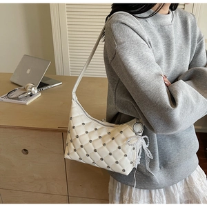 Close-up of quilted white shoulder bag with silver studs and lace pearl bow detail