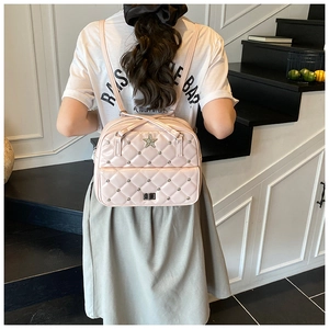 Detail of light pink quilted backpack with star buckles worn by model on stairs