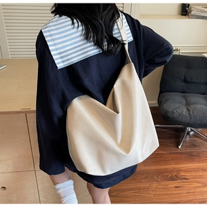 Close-up of cream white large tote bag with matte grain texture and wide shoulder strap
