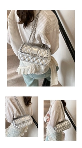 Detailed close-up of a silver quilted leather crossbody bag with metallic chain strap