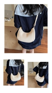 Detail view of cream half-moon shoulder bag styled in a minimalist office setting