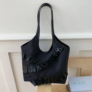 Detail of a black nylon bucket tote bag featuring three-tier pleated ruffles and D-ring straps