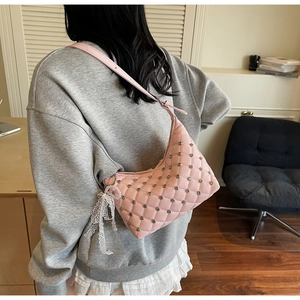 Detail of pink quilted hobo bag with rhinestone studs and pearl lace charm on strap