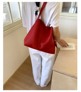 Vista posteriore della modella con borsa tote rossa in pelle a grana e outfit bianco