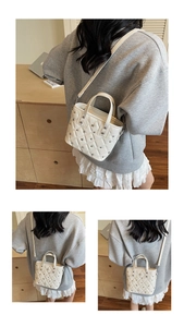 Detail view of beige quilted bucket bag with silver rivet studs and adjustable strap