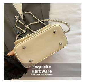 Detail view of cream handbag base with four silver metal feet and leather chain strap