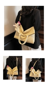 Detalle de bolso tote crema con textura, colgante de cachorro y correa de hombro ajustable