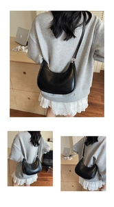 Detail view of a black crescent moon bag in glossy leather with thin shoulder strap