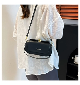 Detail of a vintage black leather box bag with gold metal buckle and white fashion text