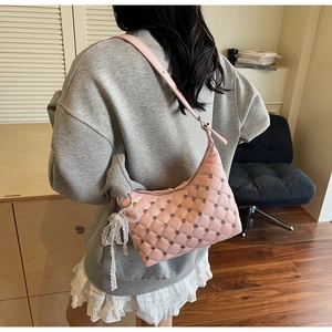 Detailed view of pink quilted shoulder bag with silver rivets and white lace bow accessory