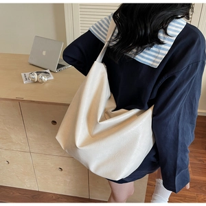 Detail of minimalist cream-colored tote bag with lychee grain texture and soft pleats