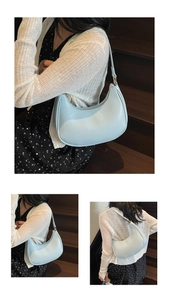 Detail of light blue PU crescent shoulder bag with golden zipper on a female model