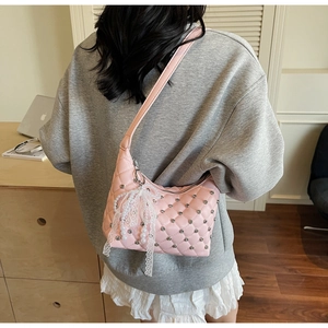 Détail d'un sac rose matelassé avec strass et pendentif nœud en dentelle délicate