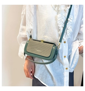 Detail of dark green leather box bag with beige woven flap and gold metal buckle