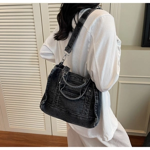Detail of black washed denim tote bag showing wide shoulder strap and vintage texture