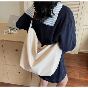 Detailed texture of off-white oversized PU leather tote bag shown in office setting