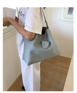 Dettaglio della borsa tote in pelle blu-grigio con fibbia a cuore e tracolla sottile