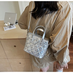 Close-up of a silver quilted bucket bag with metal studs on a model's shoulder
