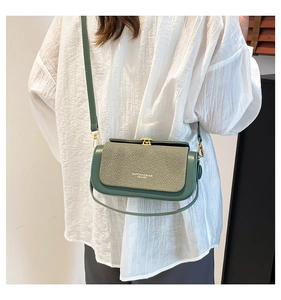 Close-up of a dark green crossbody bag with textured woven flap and golden twist lock